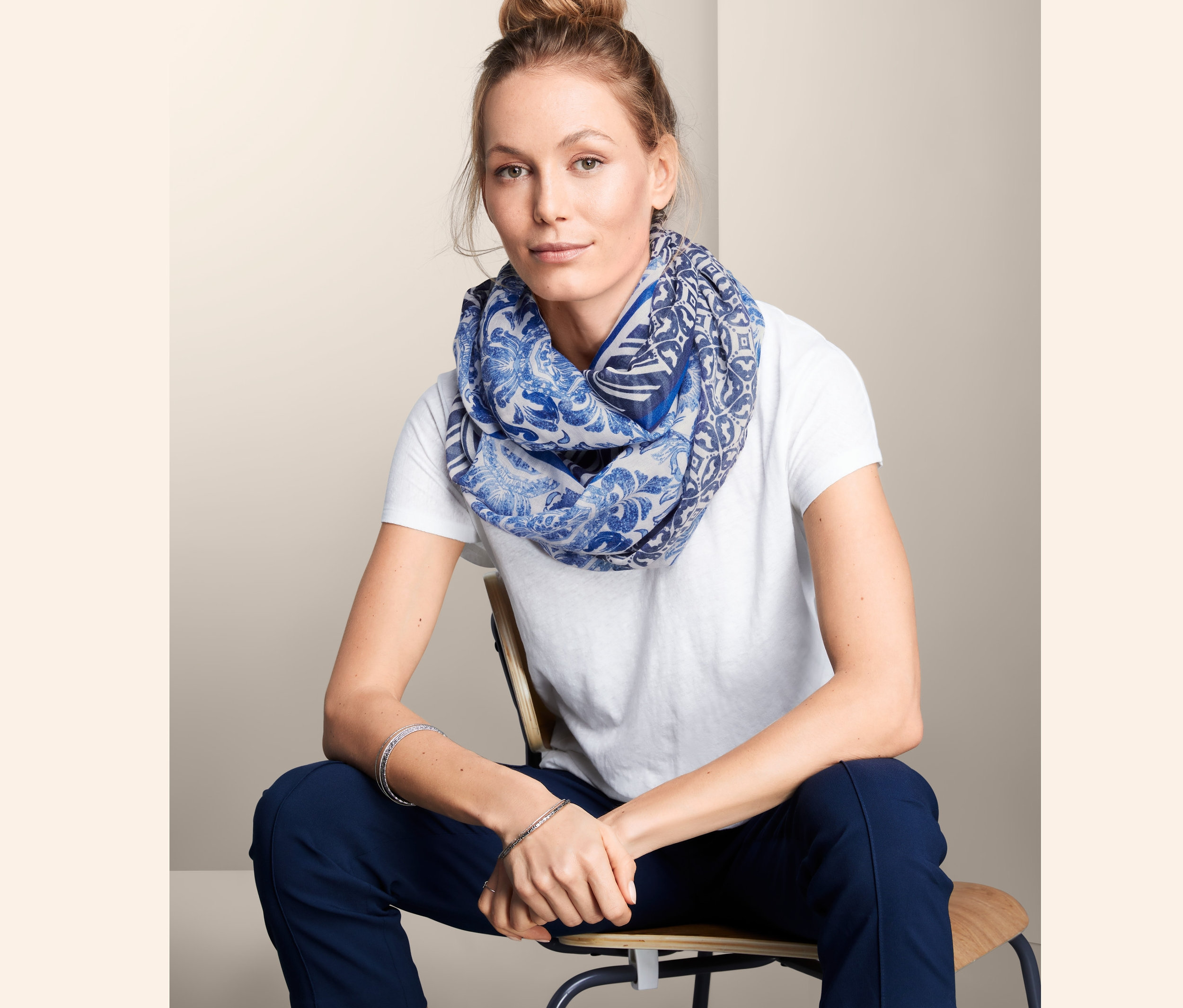 Frau sitzt und trägt einen Loop-Schal.