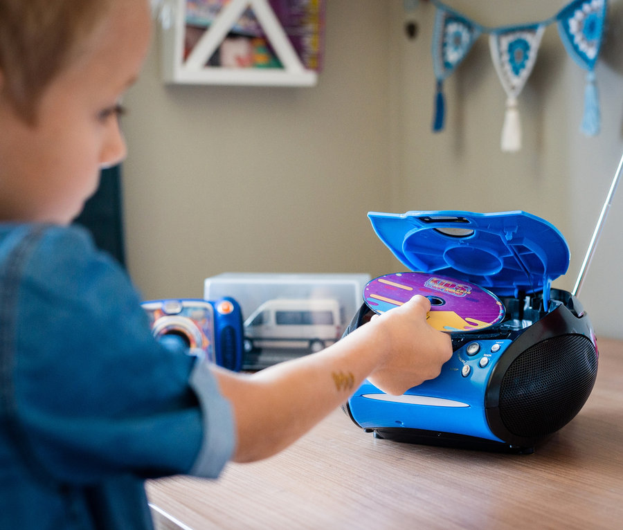 Ein Junge legt eine CD in einen blauen Lenco »SCD-24 Boombox« CD-Player mit Radio ein.