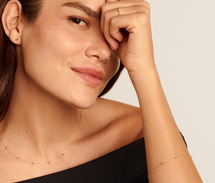 Frau mit 585 Gold Kette Kugeln, 585 Gold Ohrstecker Kugel, 585 Gold Armband Kugeln und 585 Gold Ring Kugeln und Zirkonia.