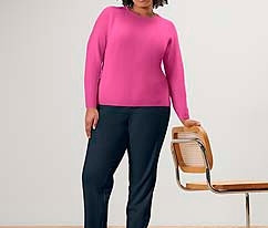 Frau steht und trägt eine Joggpants und einen pinken Strickpullover.