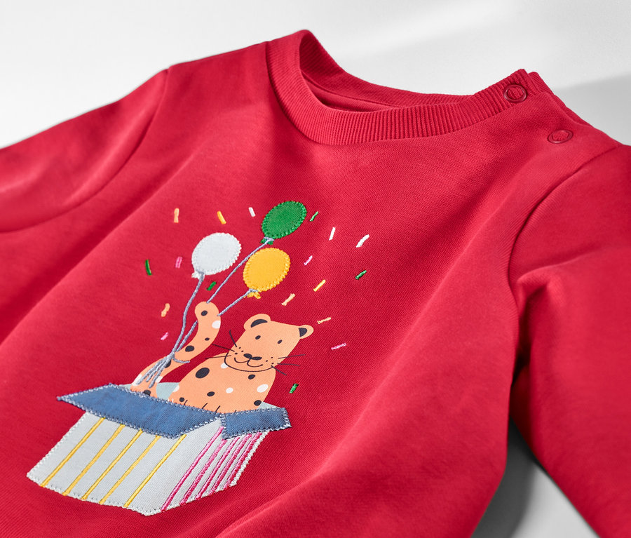 Rotes Kinder-Sweatshirt mit angerauter Innenseite und aufgenähtem Tier mit Ballons, das aus einer Kiste springt.
