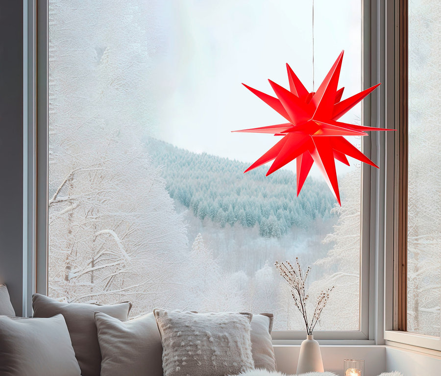 Ein roter AMARE LED-3D-Außenstern hängt vor einem Fenster mit Blick auf eine verschneite Landschaft.