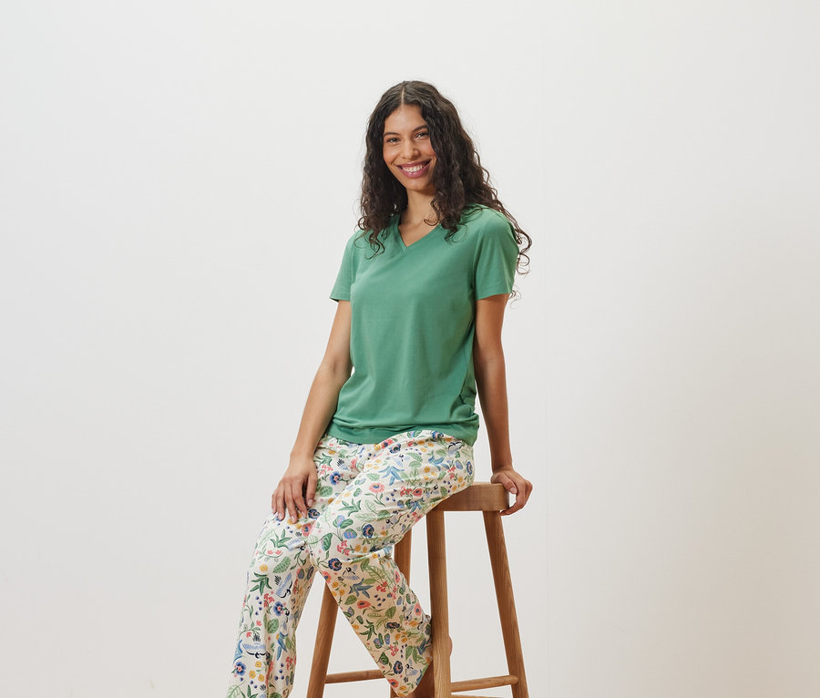 Frau sitzt auf einem Hocker und trägt ein Pyjama-Set.