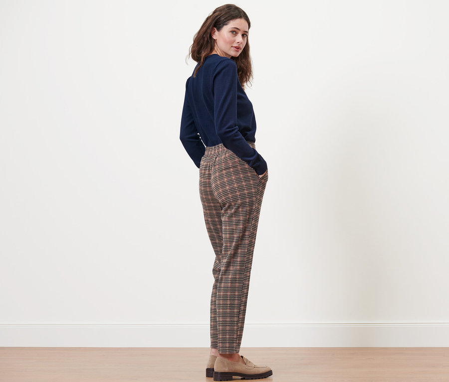 Frau posiert in Joggpants mit Hahnentritt-Dessin und blauem Pullover.