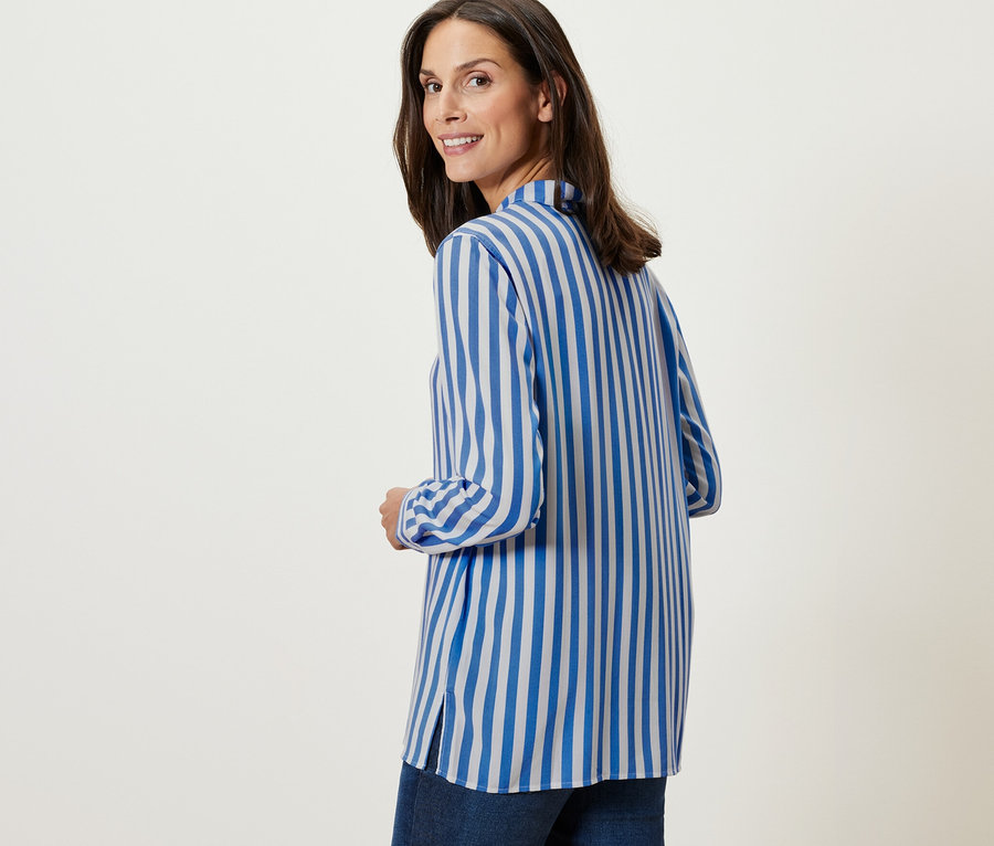 Frau blickt über die Schulter und trägt eine Gestreifte Bluse.