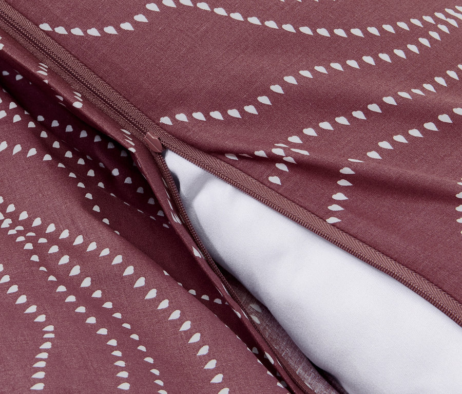 Detailaufnahme von normalgroßer, bordeauxroter Renforcé-Bettwäsche mit weißem Muster und Reißverschluss.