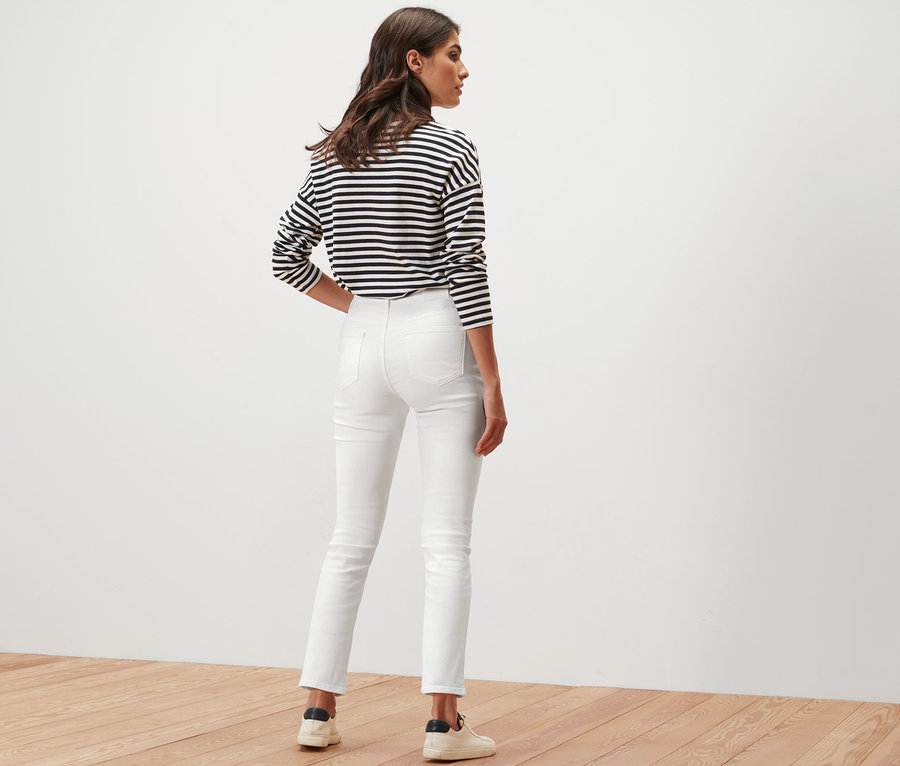 Frau posiert von hinten in einer cremefarbenen »Emma« Jeans und einem gestreiften Oberteil.