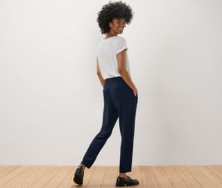 Frau posiert in marineblauer Joggpants und weißem T-Shirt.