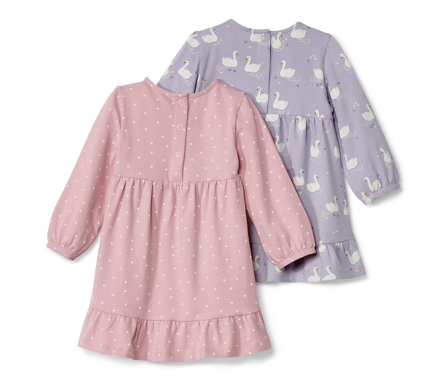 Zwei Baby-Jerseykleider: ein rosafarbenes mit weißen Punkten und ein lilafarbenes mit Schwanenprint.
