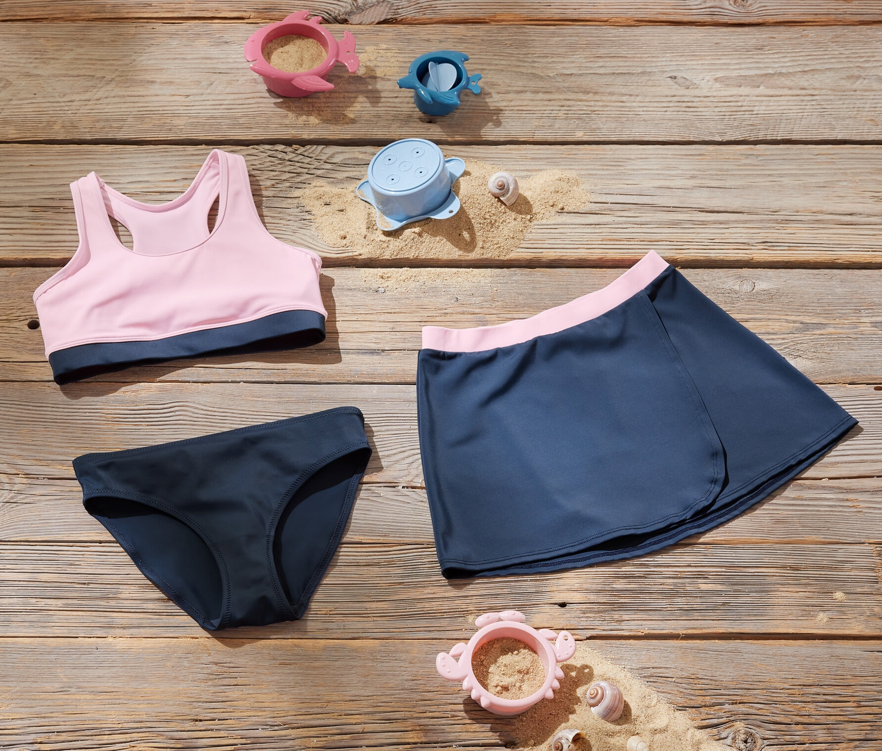 Kinder-Bikini-Set und Spielsachen auf Holzoberfläche.