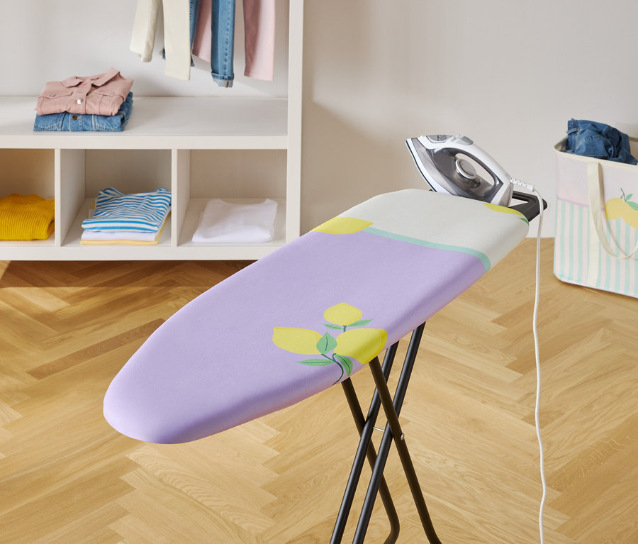 Bügeleisen auf Bügelbrett mit lila Bezug und Blumenmuster.