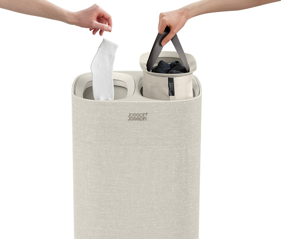 Eine Hand legt eine Socke in den Joseph Joseph »Tota«, 60 l Wäschesortierer, während eine andere Hand einen Wäschesack hält.