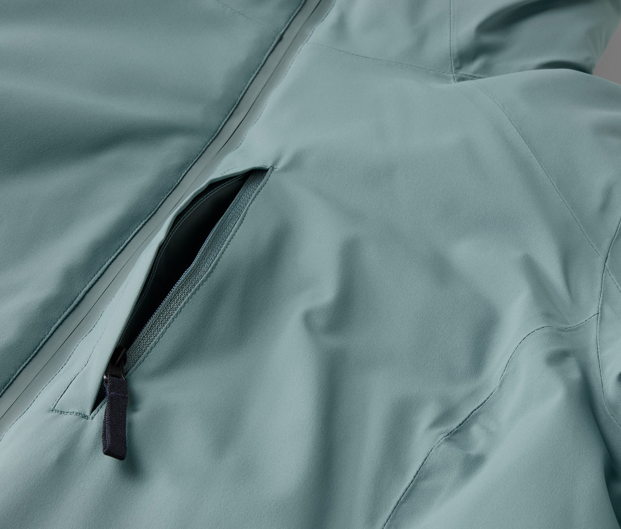 Detailaufnahme einer hellblauen Jacke mit schwarzem Reißverschluss.