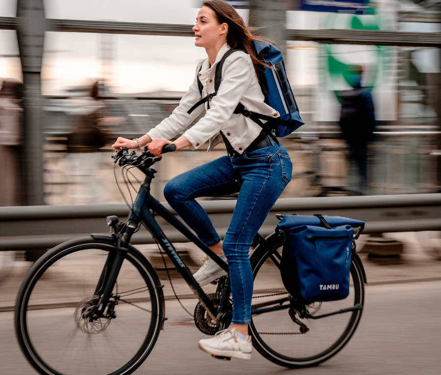 Frau fährt Fahrrad mit blauer Tambu Fahrradtasche INAYA.
