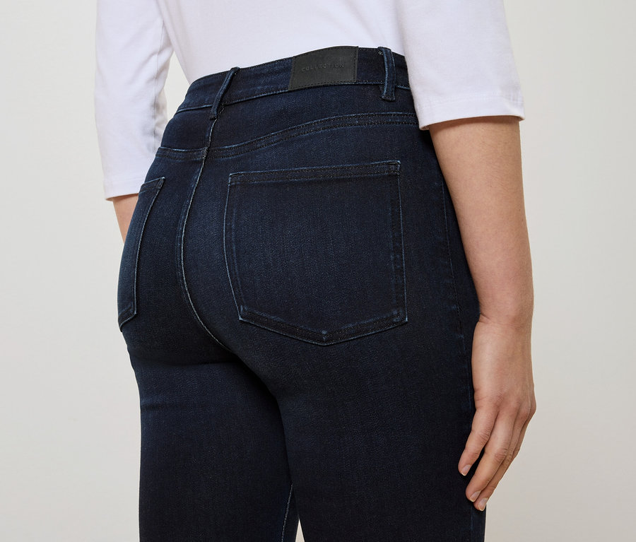 Rückansicht einer Frau in dunkelblauen Jeans und einem weißen T-Shirt.