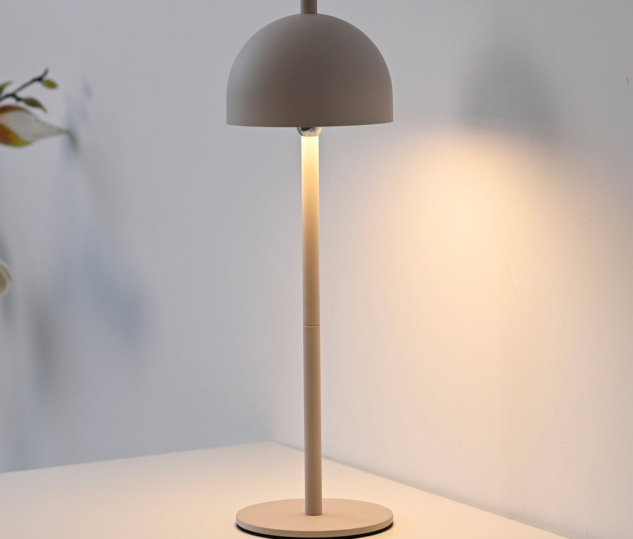 Eine beige Lampe steht auf einem weißen Tisch.