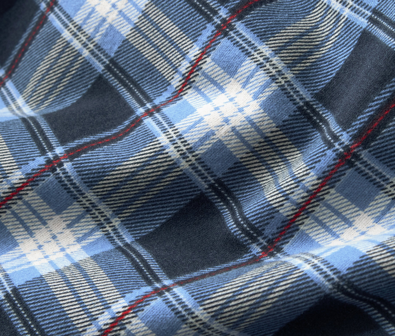Nahaufnahme eines Stoffes mit blauem Karomuster, ergänzt durch weiße und dünne rote Streifen.