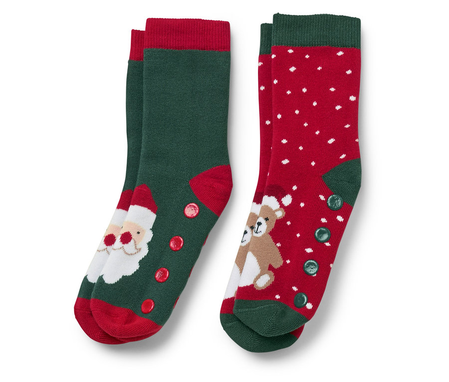 Zwei Paar Weihnachtssocken. Ein Paar ist grün mit roter Spitze und einem Weihnachtsmannbild, das andere ist rot mit weißen Punkten und einem Teddybärbild.
