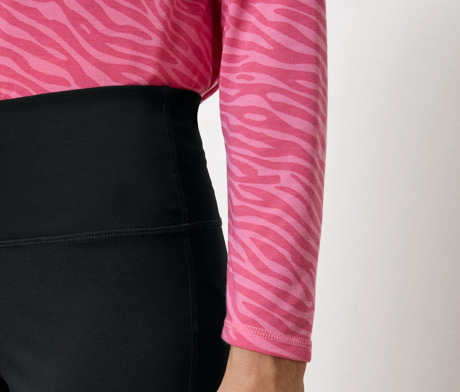 Schwarze Leggings mit hohem Bund und ein rosa Oberteil mit Animal-Print.