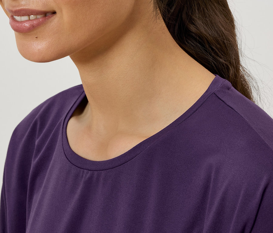 Detailaufnahme einer Frau, die ein lila T-Shirt mit Rundhalsausschnitt trägt.