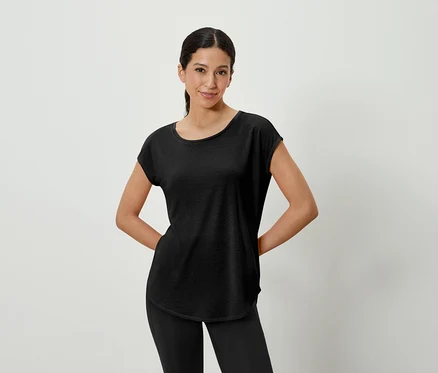 Frau posiert in schwarzem T-Shirt und Leggings.