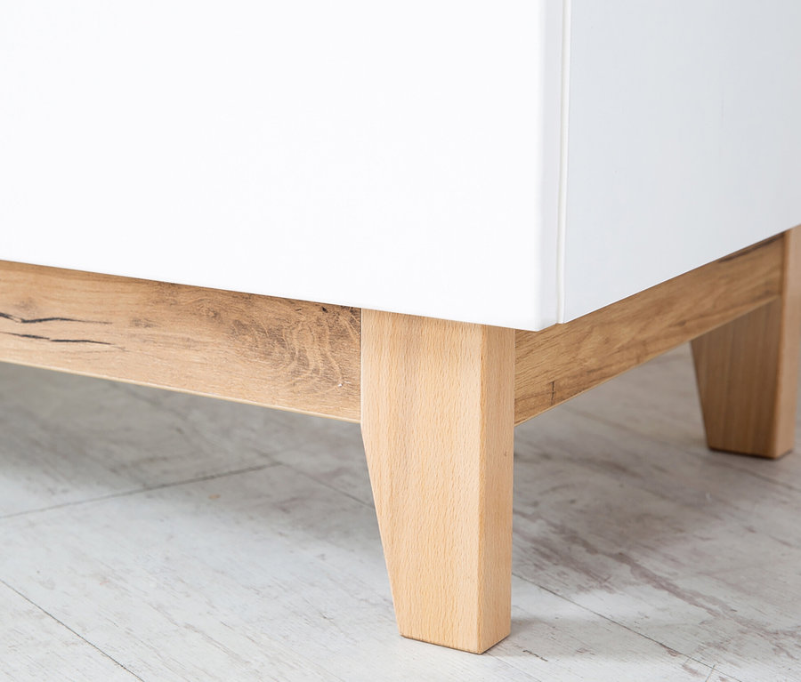 Detail einer Ecke der weißen Roba Wickelkommode »Finn« mit Holzbeinen.