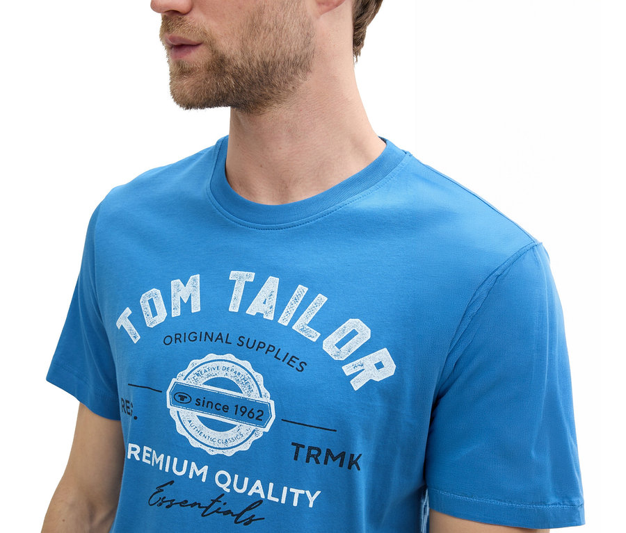 Mann trägt ein Tom Tailor T-Shirt mit Logo in Sapphire Blue.
