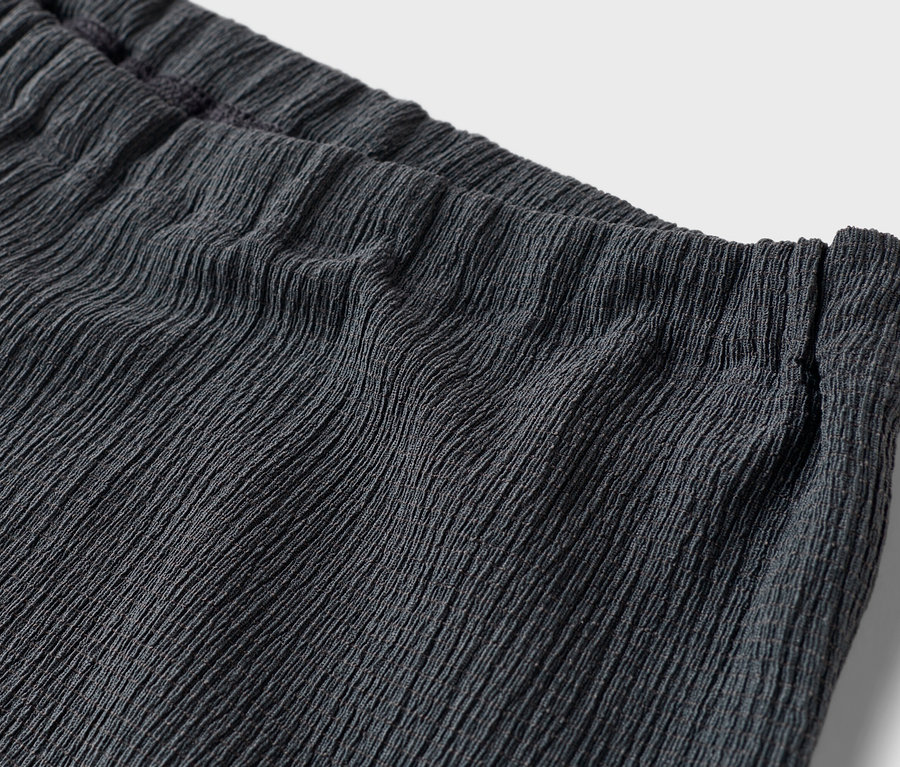 Detailaufnahme der Taille einer dunkelgrauen Hose mit elastischem Bund und horizontaler Textur.