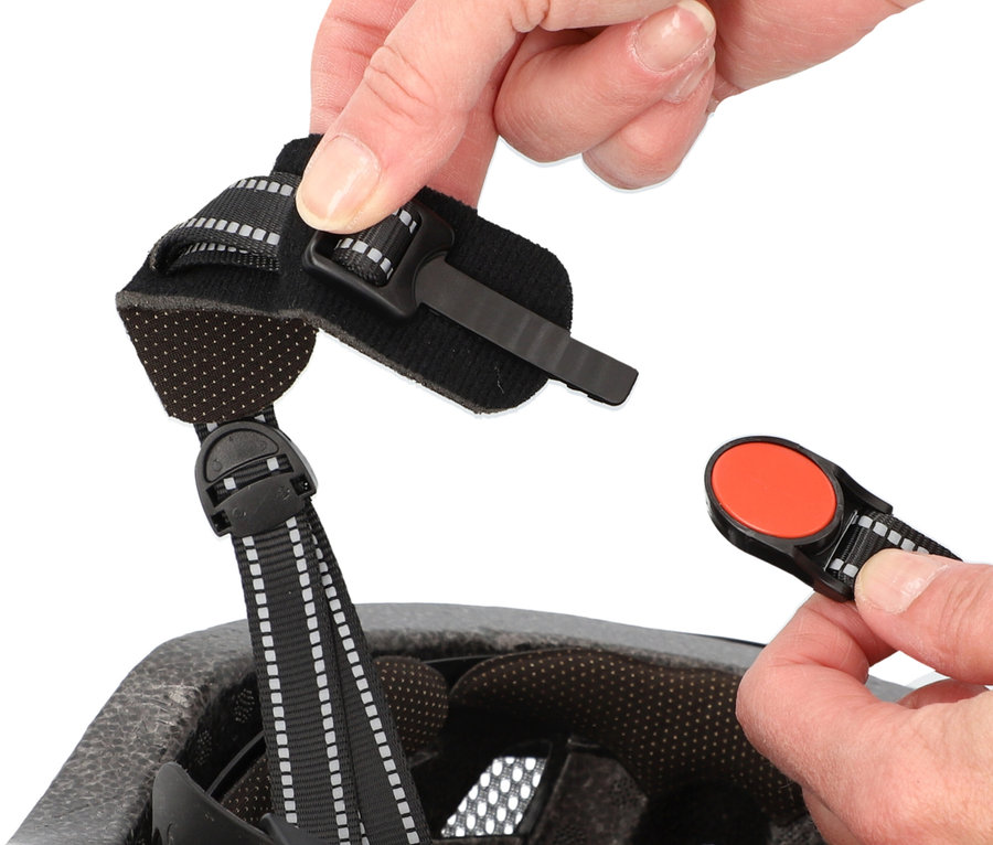 Nahaufnahme von Händen, die den Verschluss eines Fahrradhelms einstellen.