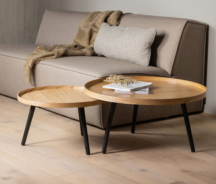 Zwei WOOOD »Mesa XL« Beistelltische aus naturfarbenem Holz stehen vor einem beigen Sofa mit Kissen und Decke.