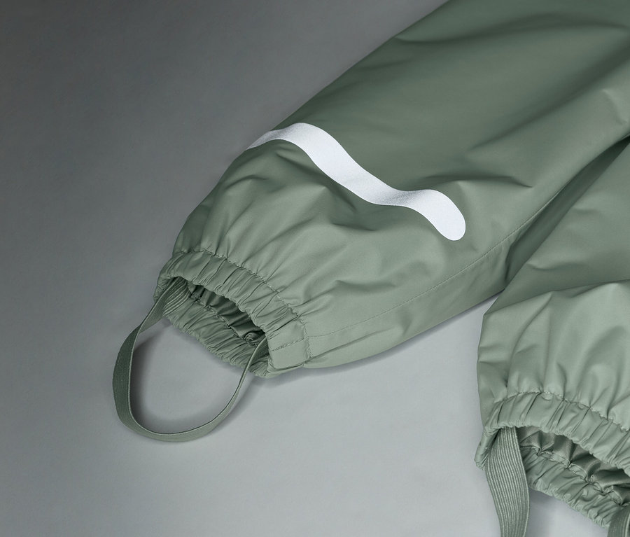 Nahaufnahme von hellgrünen Regenhosen mit weißem Logo und elastischen Bündchen.