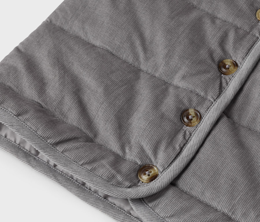 Nahaufnahme einer grauen Cordweste mit Knöpfen.