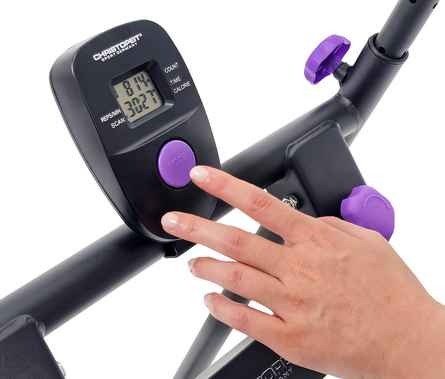Eine Hand drückt den violetten "Mode"-Knopf auf dem Display eines Christopeit Sportgeräts.