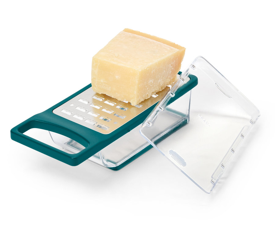 Ein Stück Käse liegt auf einer grünen Käsereibe mit Behälter.