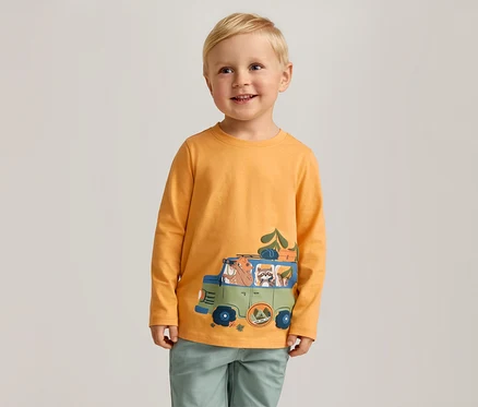 Lächelnder Junge mit blonden Haaren trägt ein orangefarbenes Langarmshirt mit einem grünen Autoaufdruck.