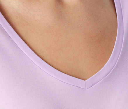 Hals und oberer Brustbereich einer Person in einem hellvioletten V-Ausschnitt-Shirt.