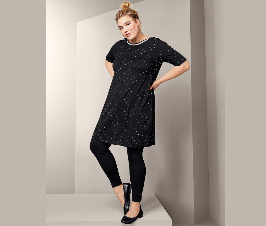 Frau posiert in schwarzen Leggings, Leder-Ballerinas und Jerseykleid im Punkte-Dessin.