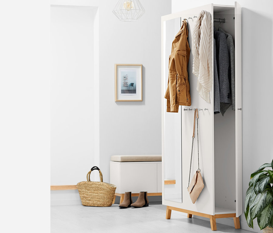 Offener multifunktionaler Flurschrank mit brauner Jacke, Schal und grauem Sakko im Inneren, eine Handtasche hängt an der Seite.