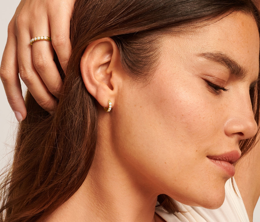 Frau trägt 585 Gold Kette Singapur, 925 Silber Creolen und Ring mit synthetischen Opalen und 925 Silber Kette mit synthetischem Opal.