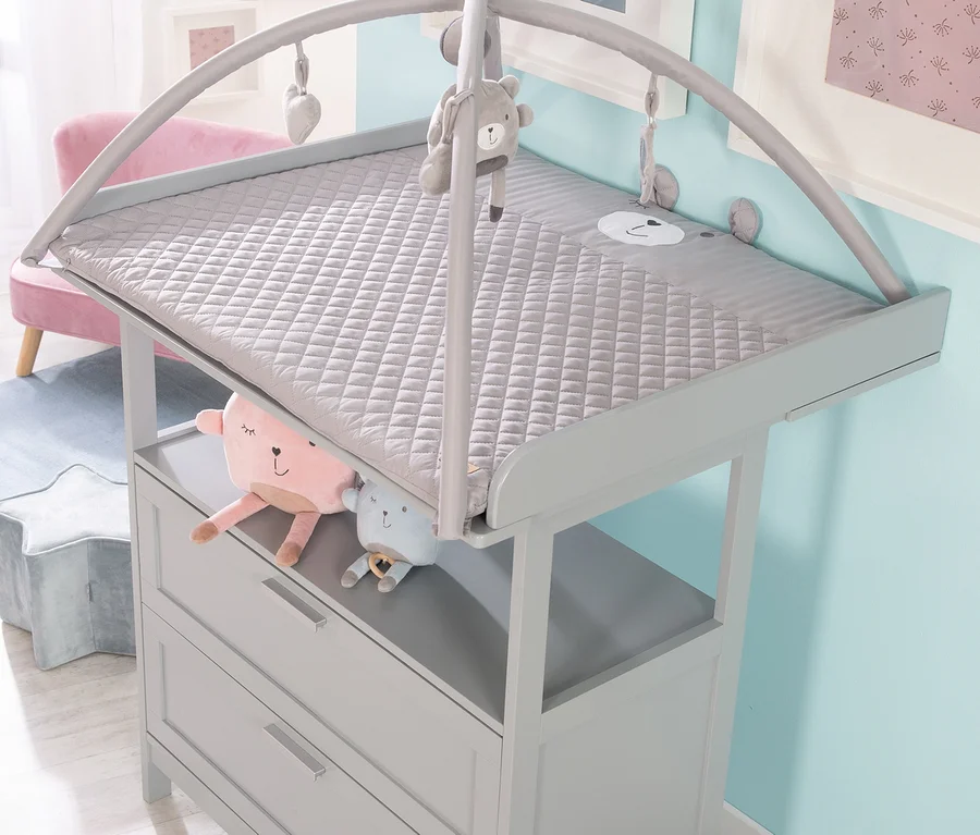 Grauer Wickeltisch mit roba Krabbeldecke mit Spielbogen und Plüschtieren.