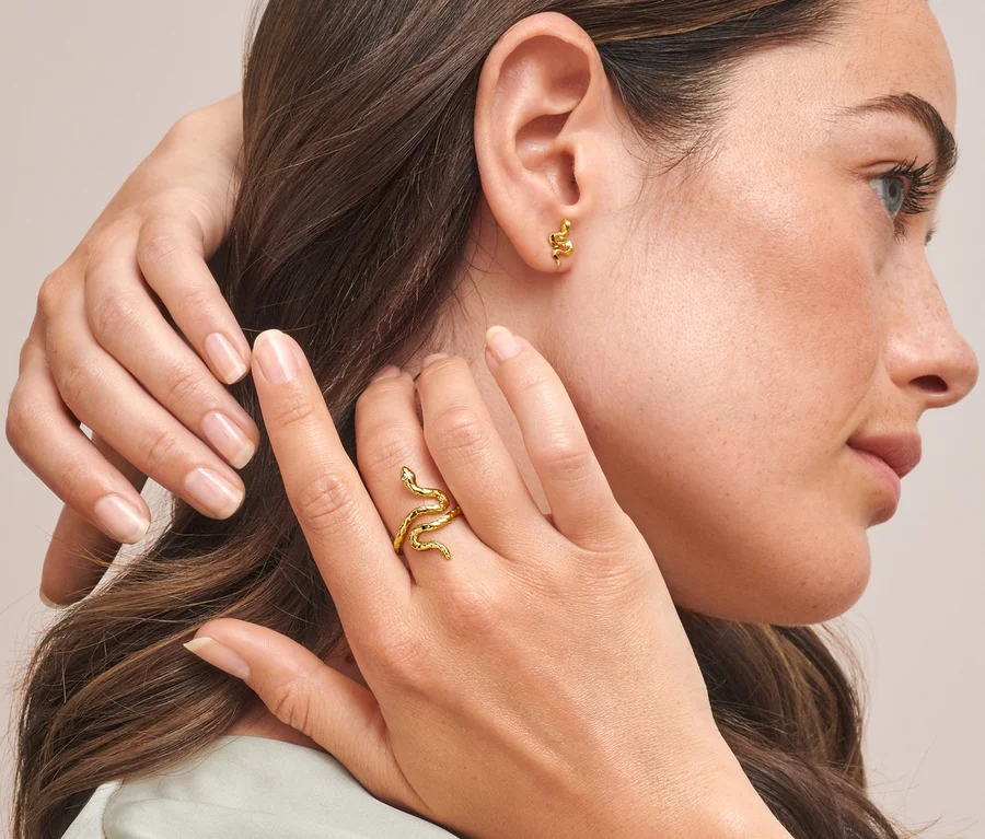 Frau mit goldenem Ring Schlange am Finger und Ohrstecker Schlange in den Ohren.