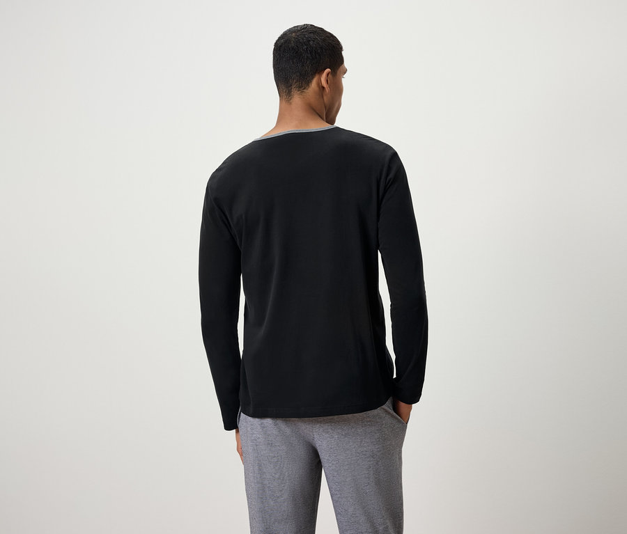 Mann von hinten trägt ein schwarzes Langarmshirt und graue Jogginghose.