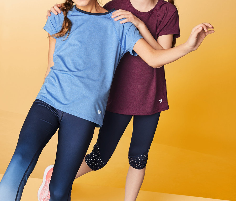 Mädchen posieren in 2 Funktionsshirts und Leggings vor gelbem Hintergrund.