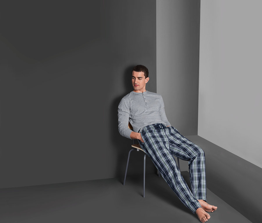 Mann sitzt auf Stuhl und trägt einen Pyjama.
