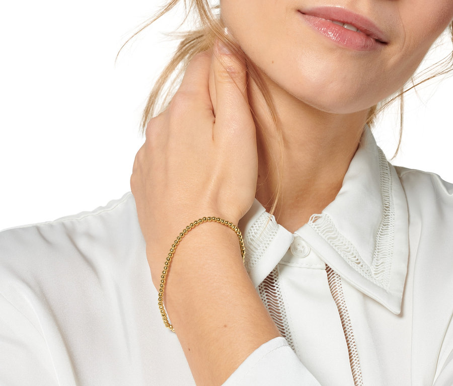 Blonde Frau berührt ihren Hals und trägt ein Armband-Set »Happy« am Handgelenk.