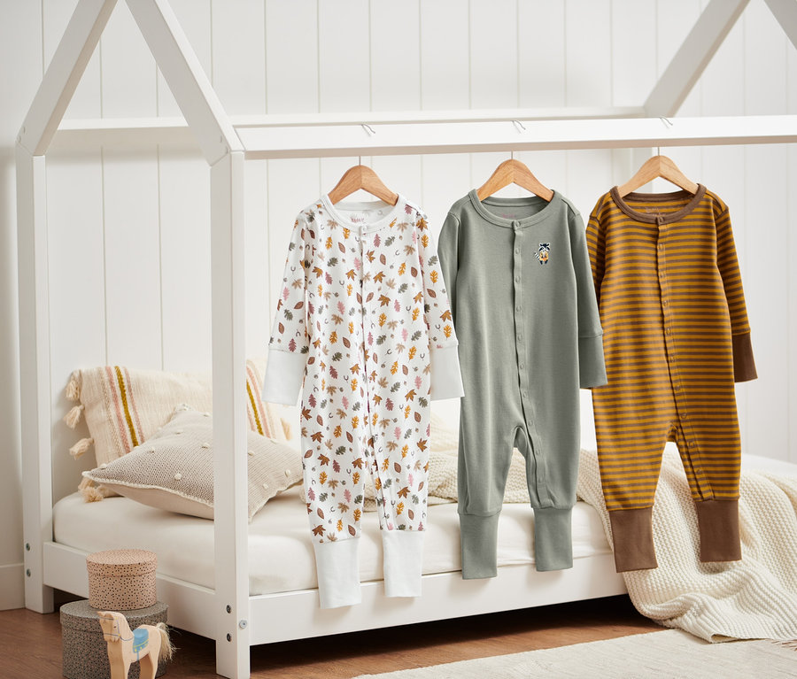 Drei Pyjamas hängen auf einem Bettgestell.