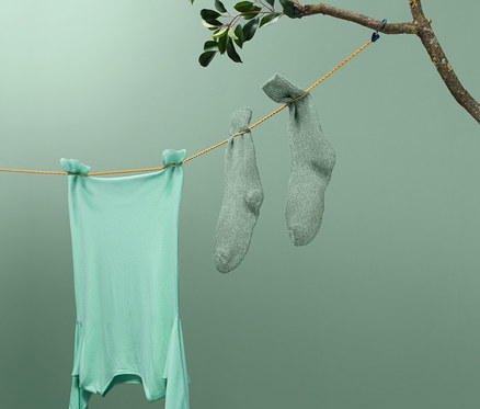 Ein grünes T-Shirt und ein Paar grüne Socken hängen auf einer Camping-Wäscheleine.
