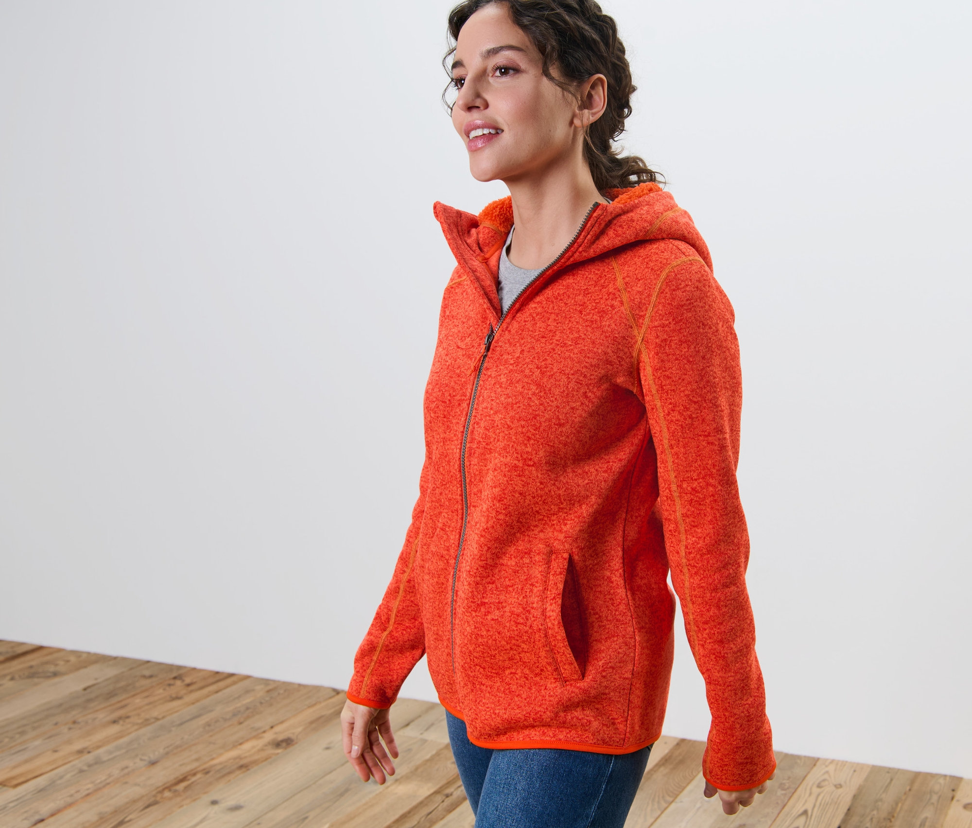 Frau trägt eine orange melierte Kapuzen-Strickfleecejacke.