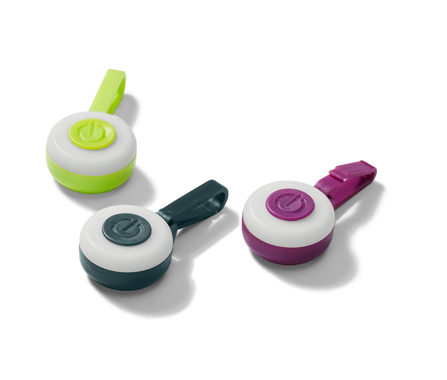 Drei LED-Anhänger in Grün, Dunkelblau und Lila liegen auf einer weißen Oberfläche.