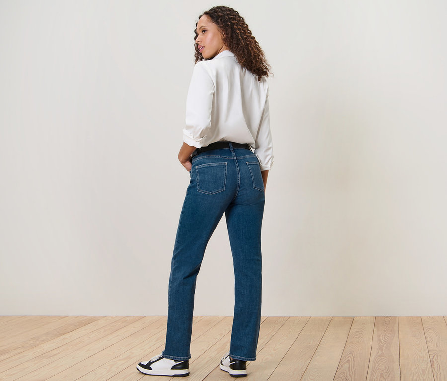 Eine Frau blickt über die Schulter und posiert in einer mitttelblauen Straight Jeans – Fit »Kira«.